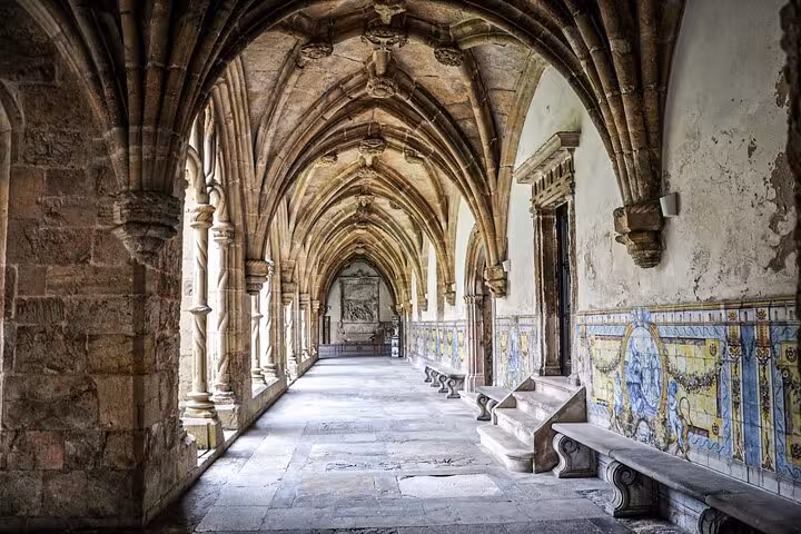 Medieval cloister with vaulted arches and tiled walls in Coimbra's historic center, ideal for exploration on a walking tour.