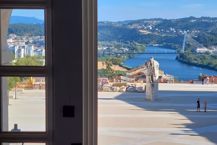 View of Coimbra from a window overlooking the river and iconic bridge, part of a private walking tour experience.