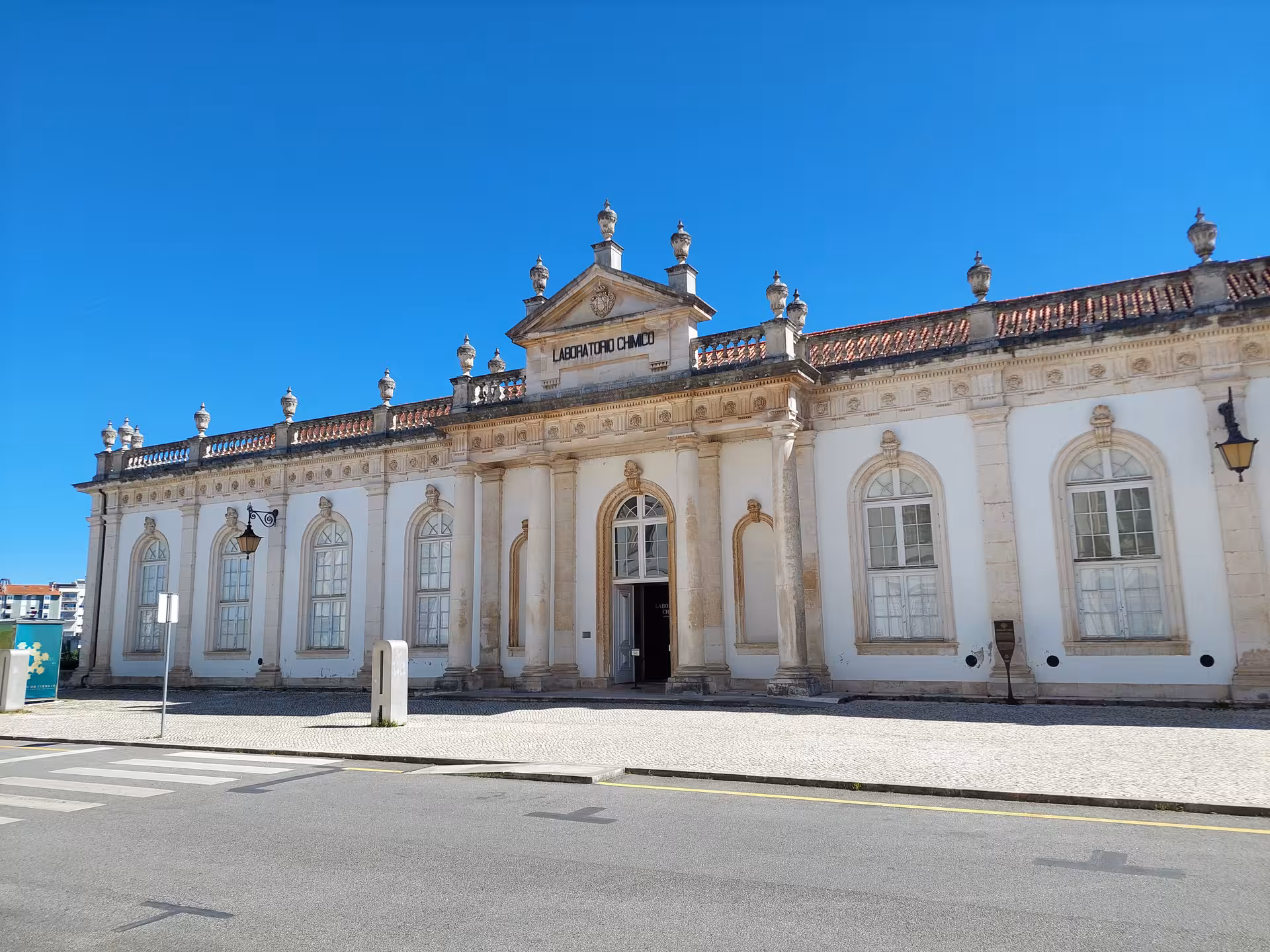 The neoclassical facade of Coimbra University's Chemistry Laboratory under a clear blue sky.