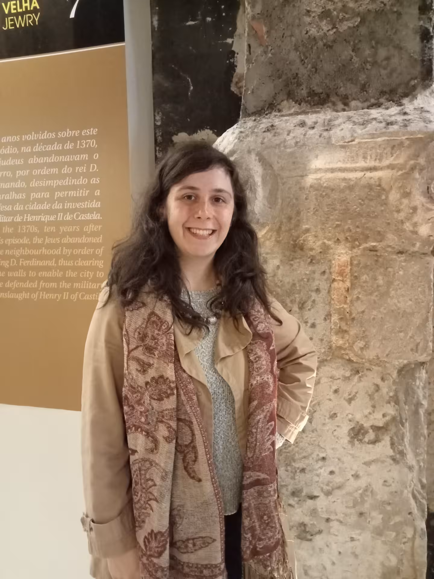 Visitor posing beside a historical display at Coimbra University, showcasing ancient architecture on a private tour.