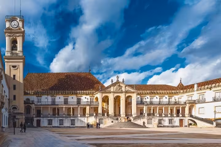 Majestic Coimbra University main building with clock tower under a vibrant sky, featured in the walking tour.