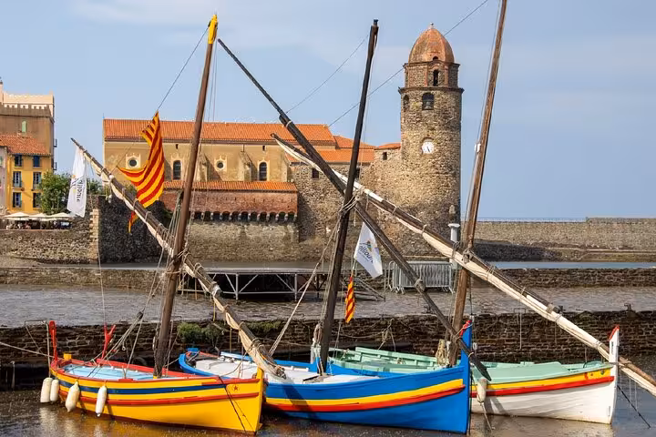 Colorful traditional fishing boats moored in Collioure harbor with the historic Church of Notre-Dame-des-Anges behind