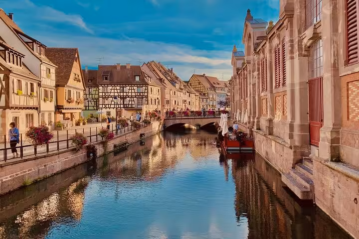 Colmar canal with colorful half-timbered houses and flower-lined promenade in Alsace, France