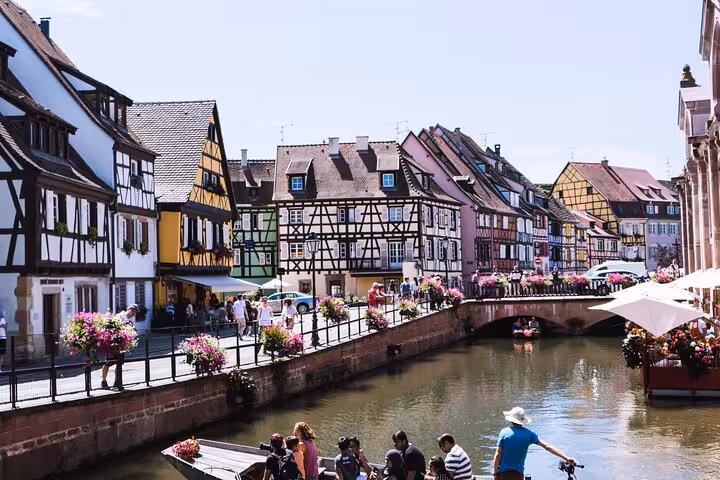 Colorful half-timbered houses along the canal in Colmar, Alsace, France with tourists on a boat