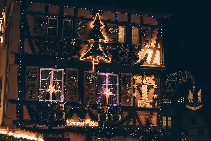 Colmar half-timbered building decorated with Christmas lights and Bonnes Fêtes neon sign at night