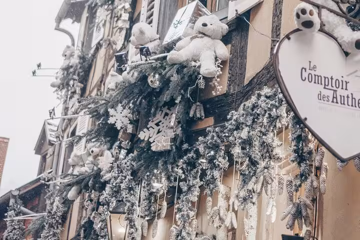 Christmas decorations with white teddy bears and snowy garlands on a shop facade in Colmar, France