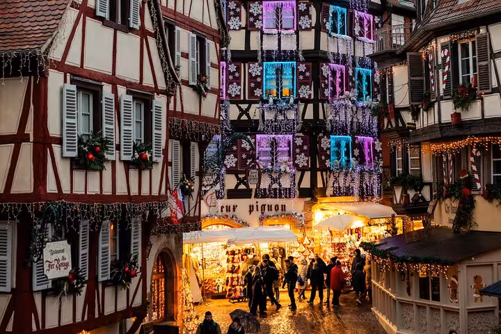 Colmar Christmas market with half-timbered buildings decorated with festive lights and snowflake ornaments at dusk