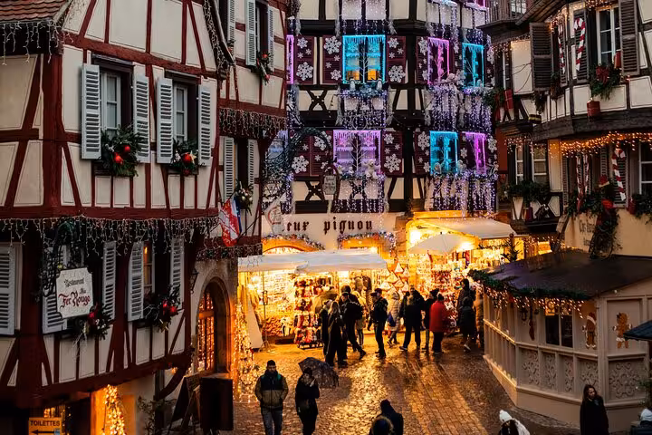 Colmar Christmas market with half-timbered buildings decorated with festive lights and holiday stalls at dusk