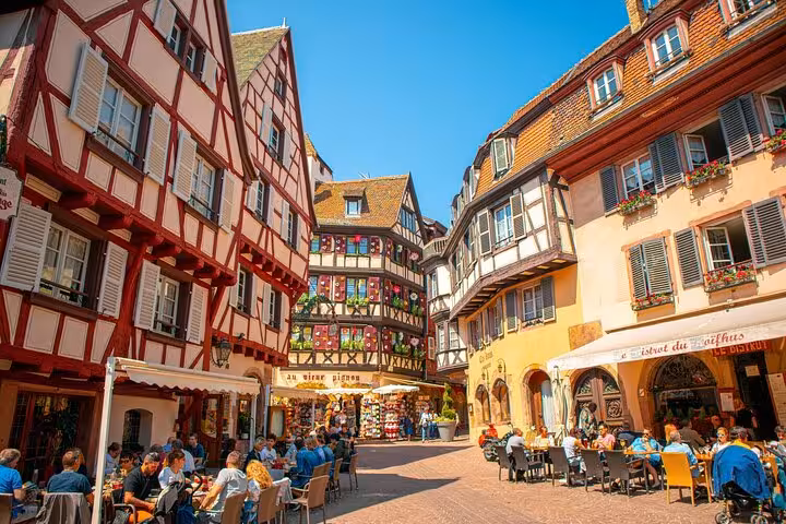 Colorful half-timbered buildings and outdoor café terraces in Colmar's historic town square, Alsace, France
