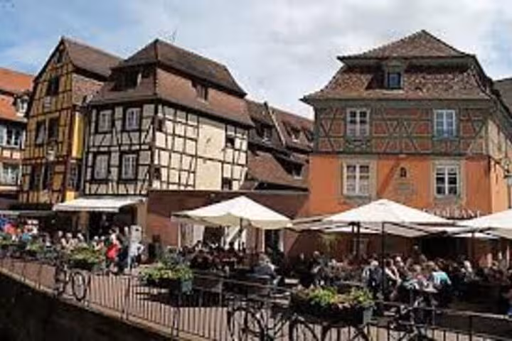 Half-timbered buildings and outdoor restaurant terraces along the waterfront in Colmar, Alsace, France