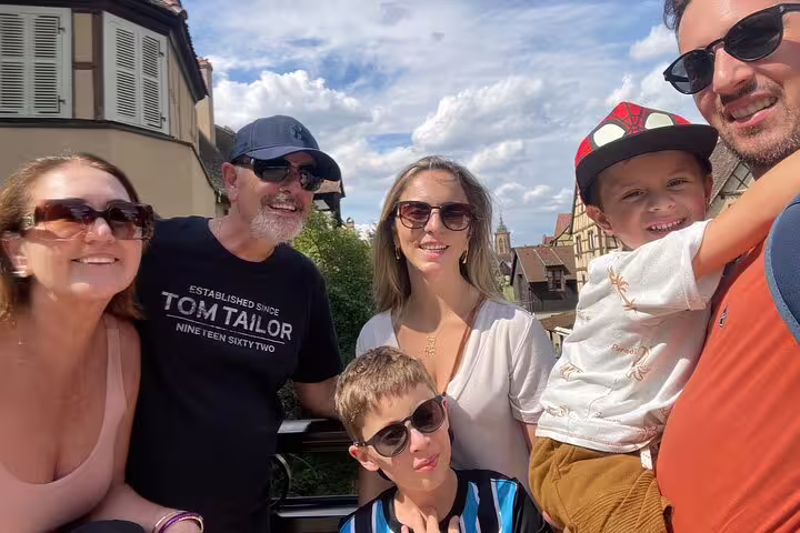Family group photo in Colmar old town during a self-guided scavenger hunt, with half-timbered houses