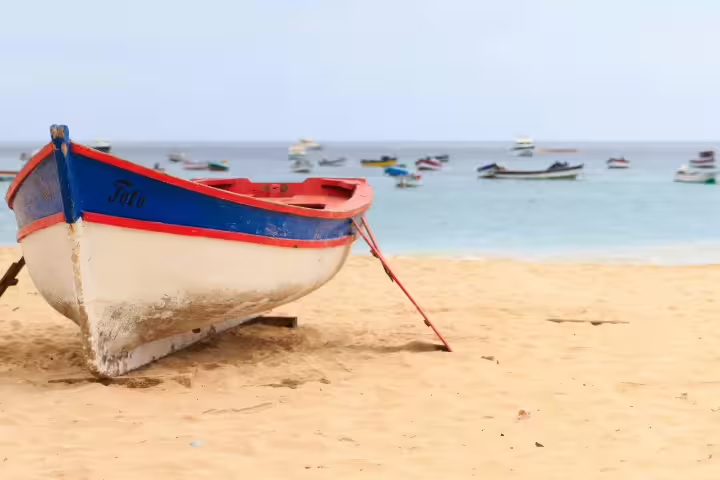 Colorful boat on sandy beach in Cape Verde with ocean view, perfect for Sao Vicente and Santo Antao island tours.