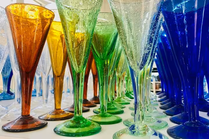 Colorful blown glass champagne flutes in amber, green, and cobalt blue on display in Antibes, French Riviera