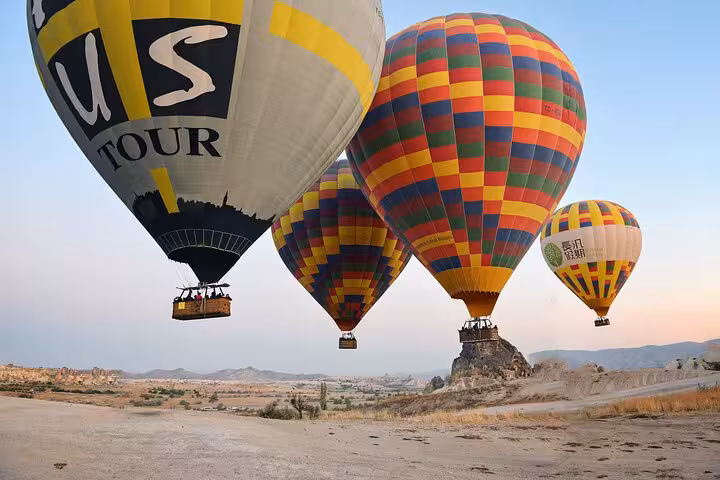 Colorful hot air balloons flying low over Cappadocia landscape at sunrise on a balloon tour in Turkey