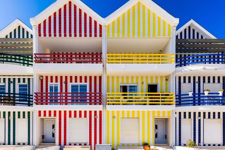 Colorful striped houses in Costa Nova, Portugal, showcase vibrant architecture perfect for memorable photo opportunities.