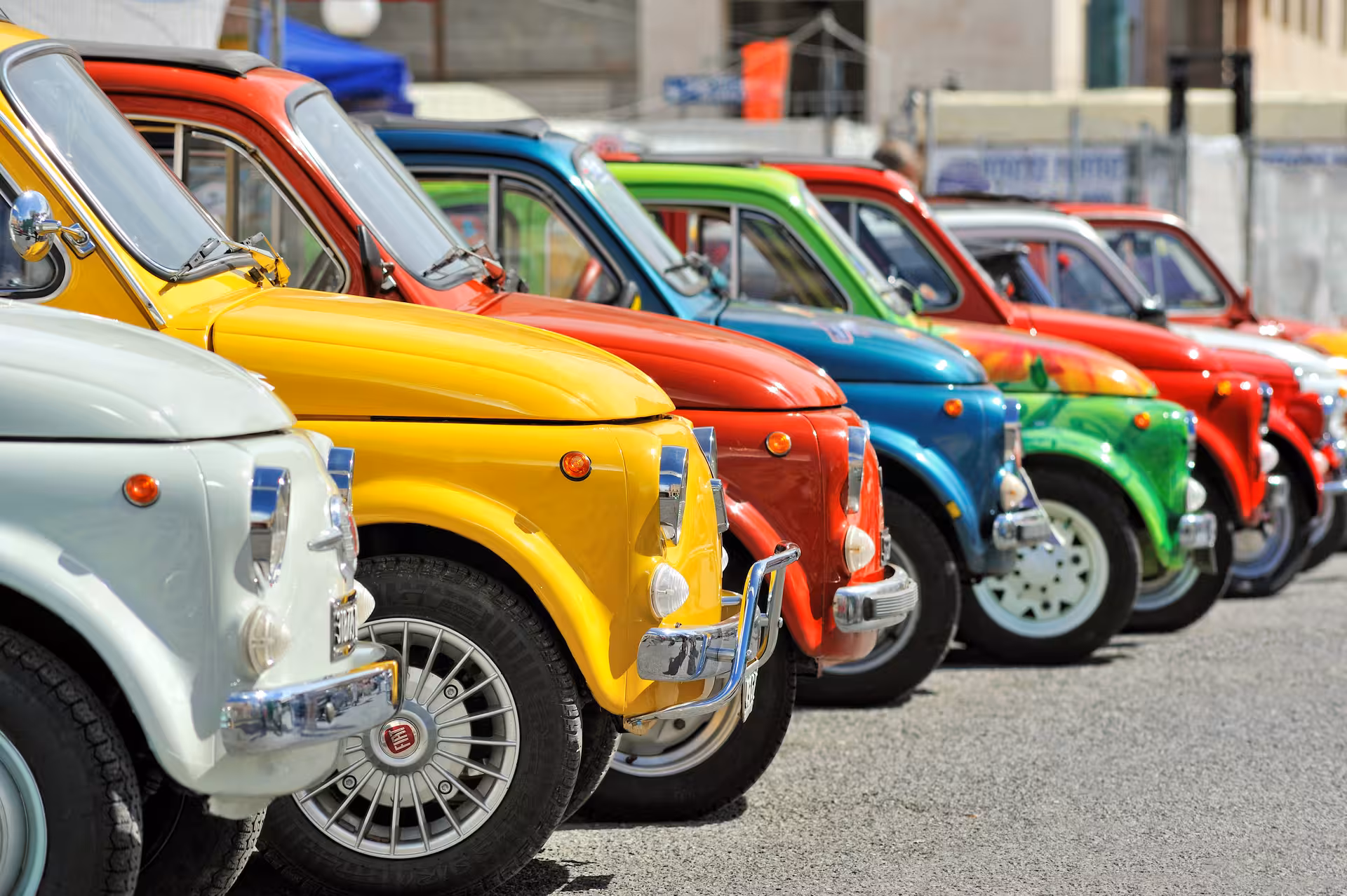 Lineup of colorful vintage FIAT 500 cars, showcasing vibrant hues under the Tuscan sun for a unique driving experience.