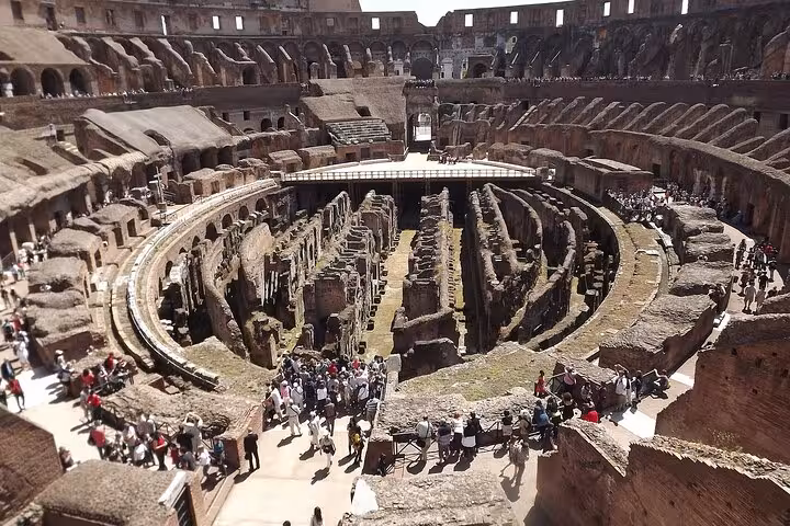 Aerial view of the Colosseum's ancient arena, showcasing its historic architecture and bustling tourist activity.
