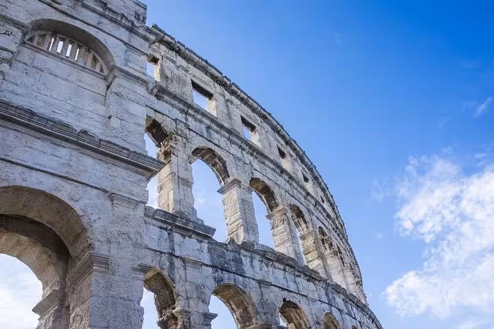 Colosseum's ancient arches stand tall against a clear blue sky, perfect for the Ancient Rome Express Tour experience.