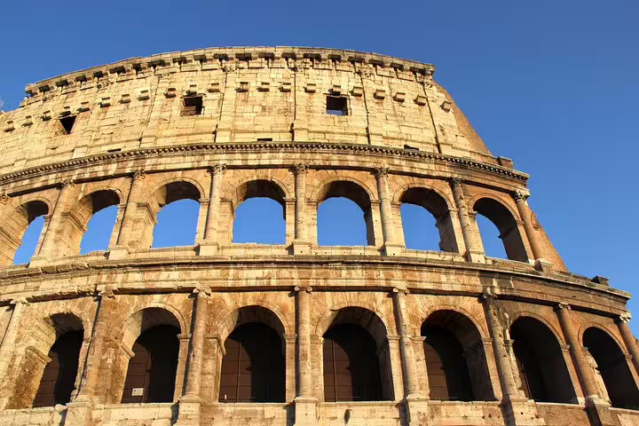Close-up of the Colosseum’s ancient arches at sunset in Rome, highlighting details explored on a small-group guided tour