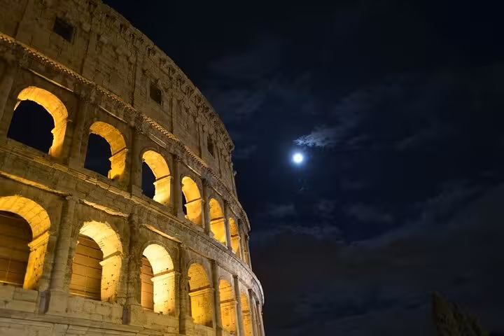 The Colosseum illuminated under a full moon, showcasing its majestic architecture on the Ancient Rome Express Tour.