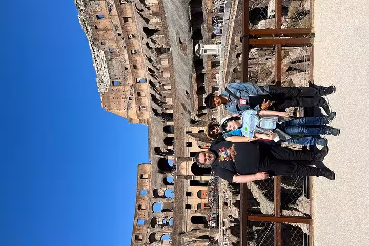 Tourists stand on the historic arena floor of the Colosseum, experiencing a unique perspective of Roman history.