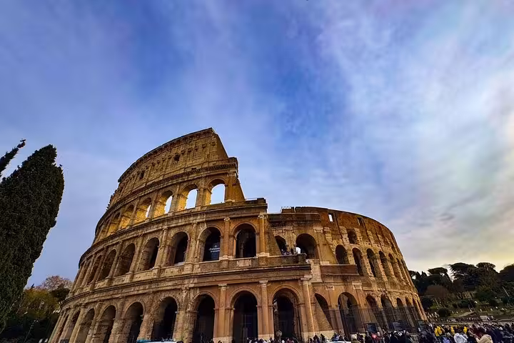 Experience the grandeur of the Colosseum's exterior under a vast sky, perfect for an engaging audio guide tour.