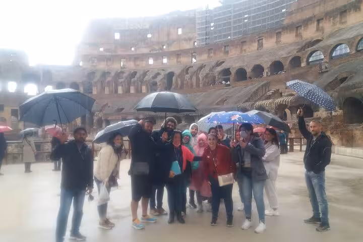 Tourists enjoying a guided Colosseum tour in Rome despite the rain, showcasing the iconic ancient amphitheater.