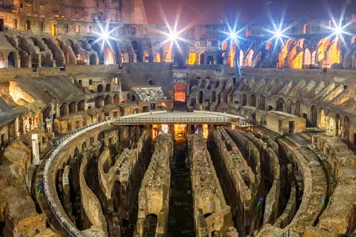 Illuminated interior view of the Colosseum at night showcasing ancient architecture on the Rome guided tour.