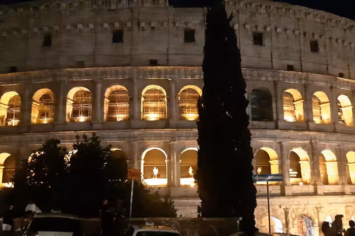 Night view of illuminated Colosseum arches in Rome, highlighting the grandeur of ancient Roman architecture.