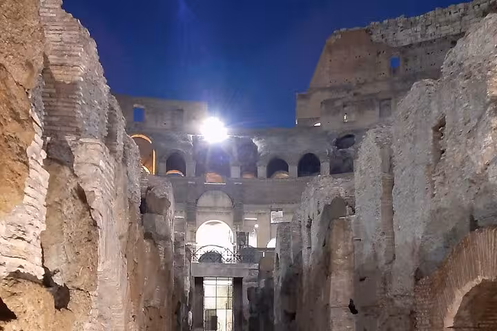 Experience the historic underground passages of the Colosseum beautifully lit during a night guided tour in Rome.