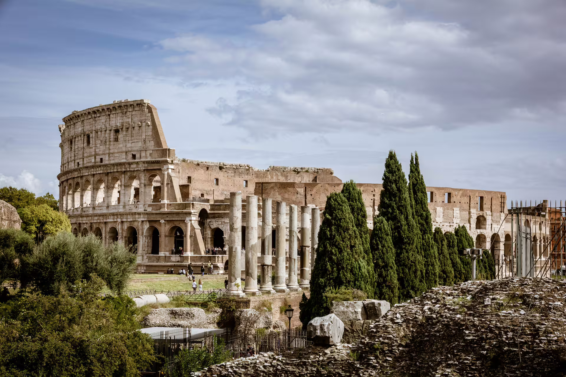 View of the Colosseum and Roman Forum ruins on a sunny day, highlight stop on a private luxury vehicle tour of Rome