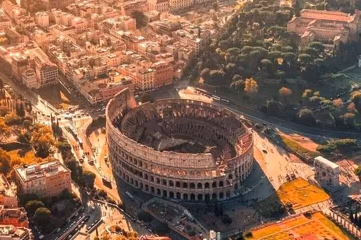 Aerial view of the Colosseum in Rome at sunset, highlighting its majestic architecture and surrounding cityscape.