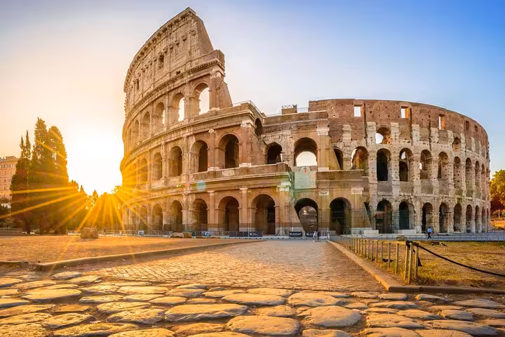 Sunset view of the Colosseum in Rome, highlighting its ancient architecture, included in our tour package with tickets.