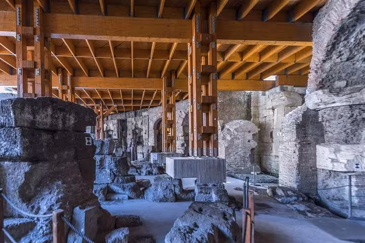 Colosseum underground area with wooden support structures and ancient stone remnants on a guided tour.