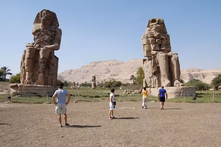 Colossi of Memnon statues in Luxor with visitors, featured on a private day tour from Hurghada