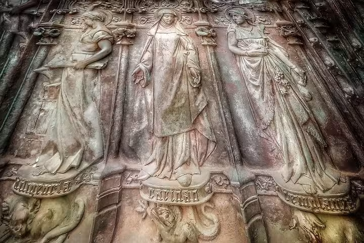 Intricate stone carvings of historical figures on a facade in Comillas, showcasing exquisite craftsmanship and detail.