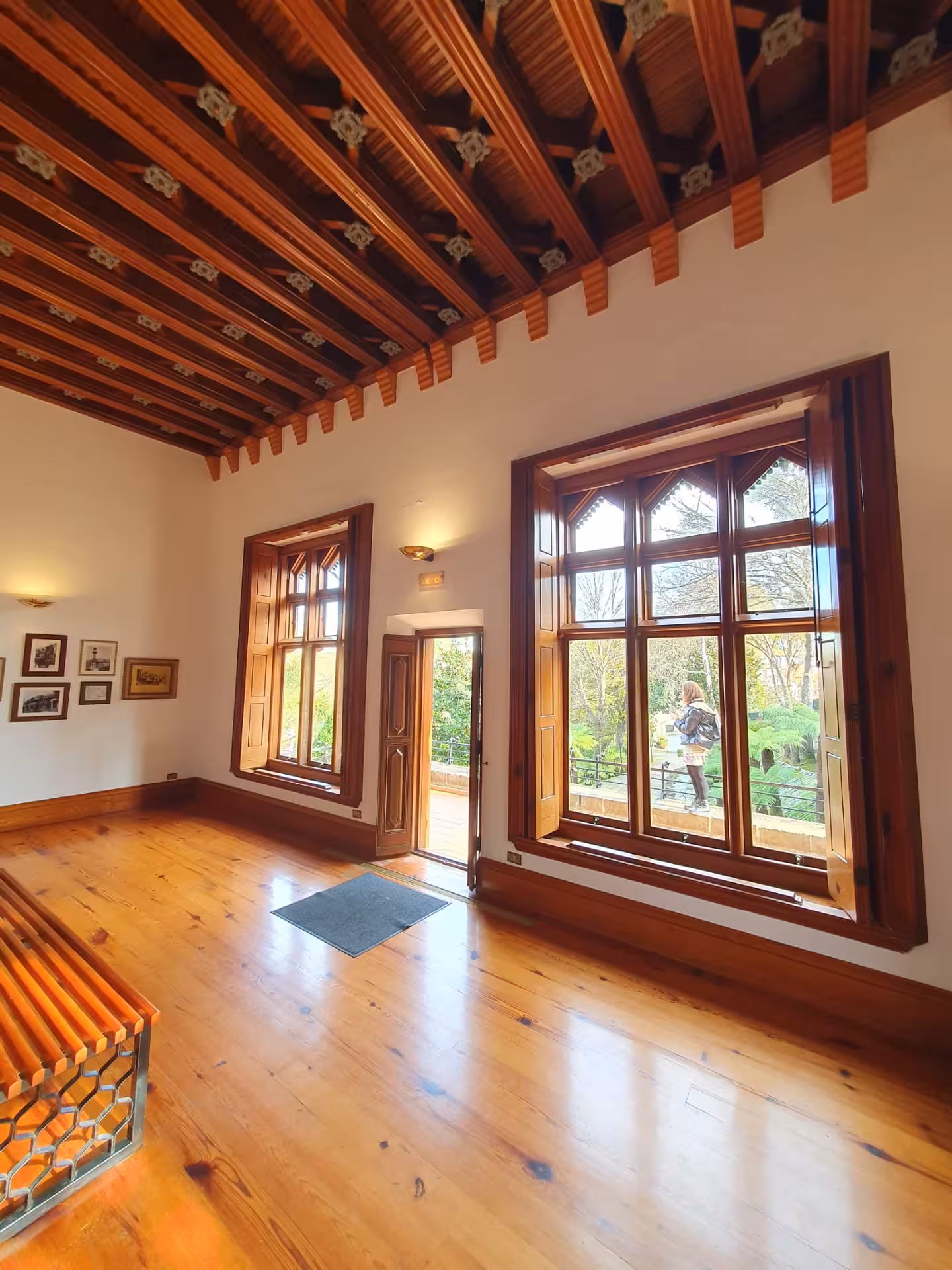 Elegant interior of a modernist building in Comillas with wooden floors and large windows overlooking gardens.