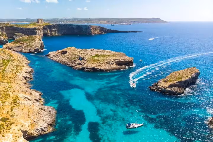 Aerial view of Comino Blue Lagoon and rocky islets with speedboat trail, highlight of Malta Gozo half-day tour