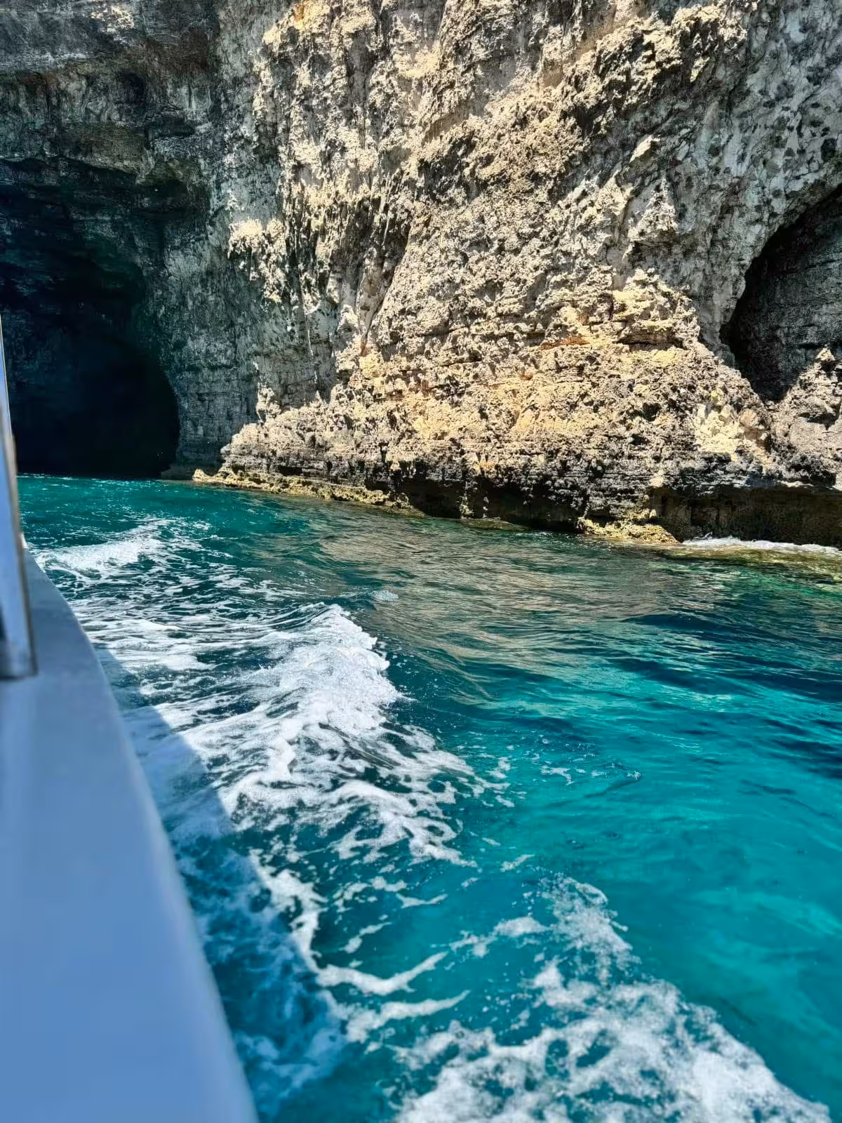 Boat cruising past Comino sea caves and rugged cliffs over turquoise water on Blue Lagoon sunset tour