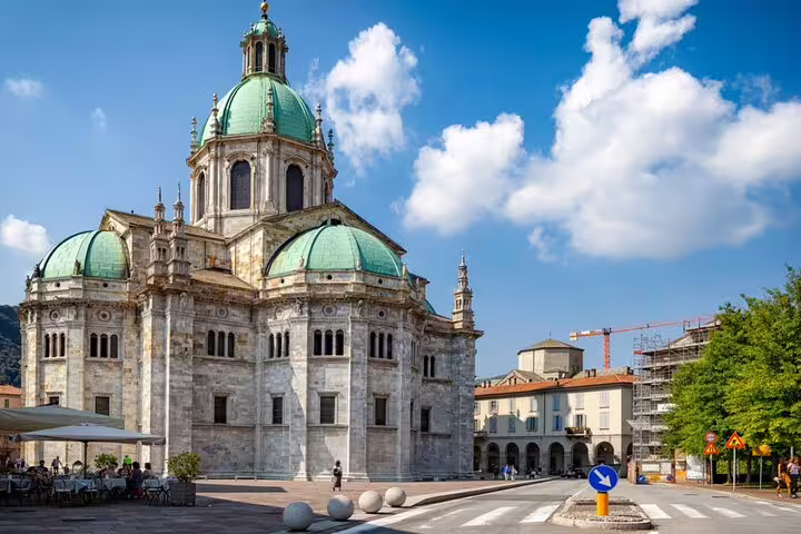 Como Cathedral with green copper domes and marble facade on a sunny day in Como, Italy
