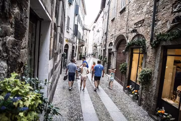 Visitors strolling a cobbled lane in Como historic center, perfect add-on to a Lake Como guided boat tour