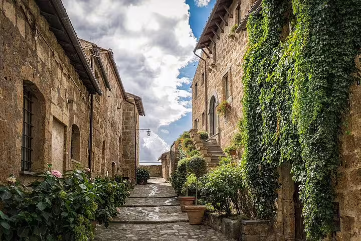 Narrow cobblestone alley flanked by ivy-covered stone buildings in an Italian medieval village