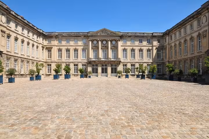 Cobblestone courtyard of Compiègne Palace with classical French architecture and potted trees