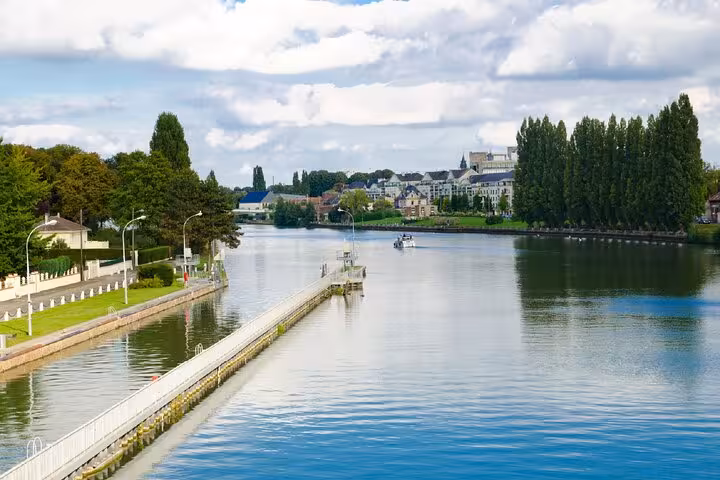 Calm river with a pier and historic buildings along the waterfront in Compiègne, France