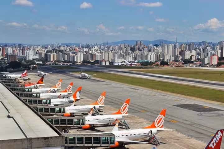 Airplanes lined up at Congonhas Airport runway with São Paulo skyline, showcasing transfer convenience to city hotels.