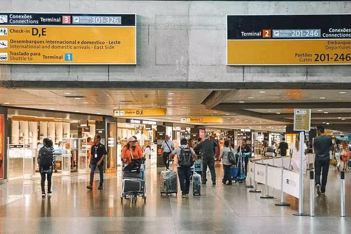 Passengers with luggage navigating through bustling terminal at Congonhas Airport, São Paulo.