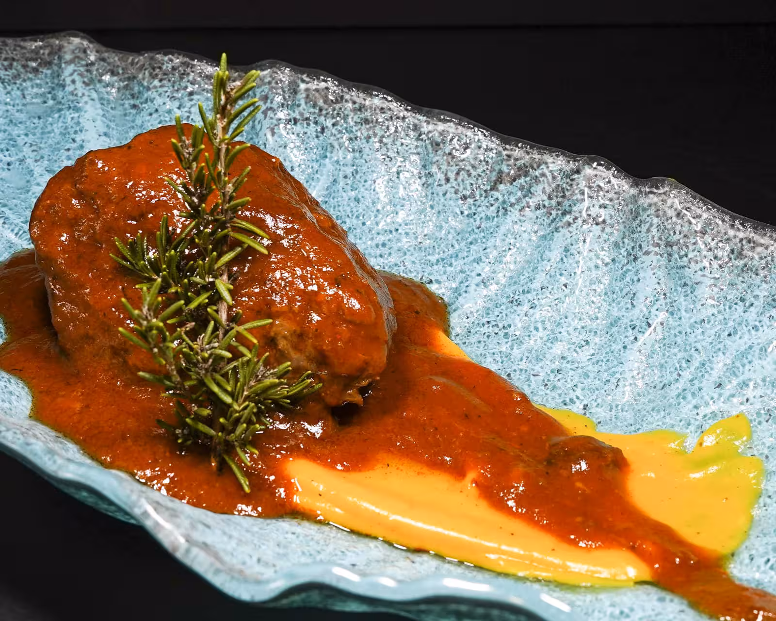 Succulent beef in red sauce with creamy puree, showcasing gourmet flavors at the Conil Beef Festival.
