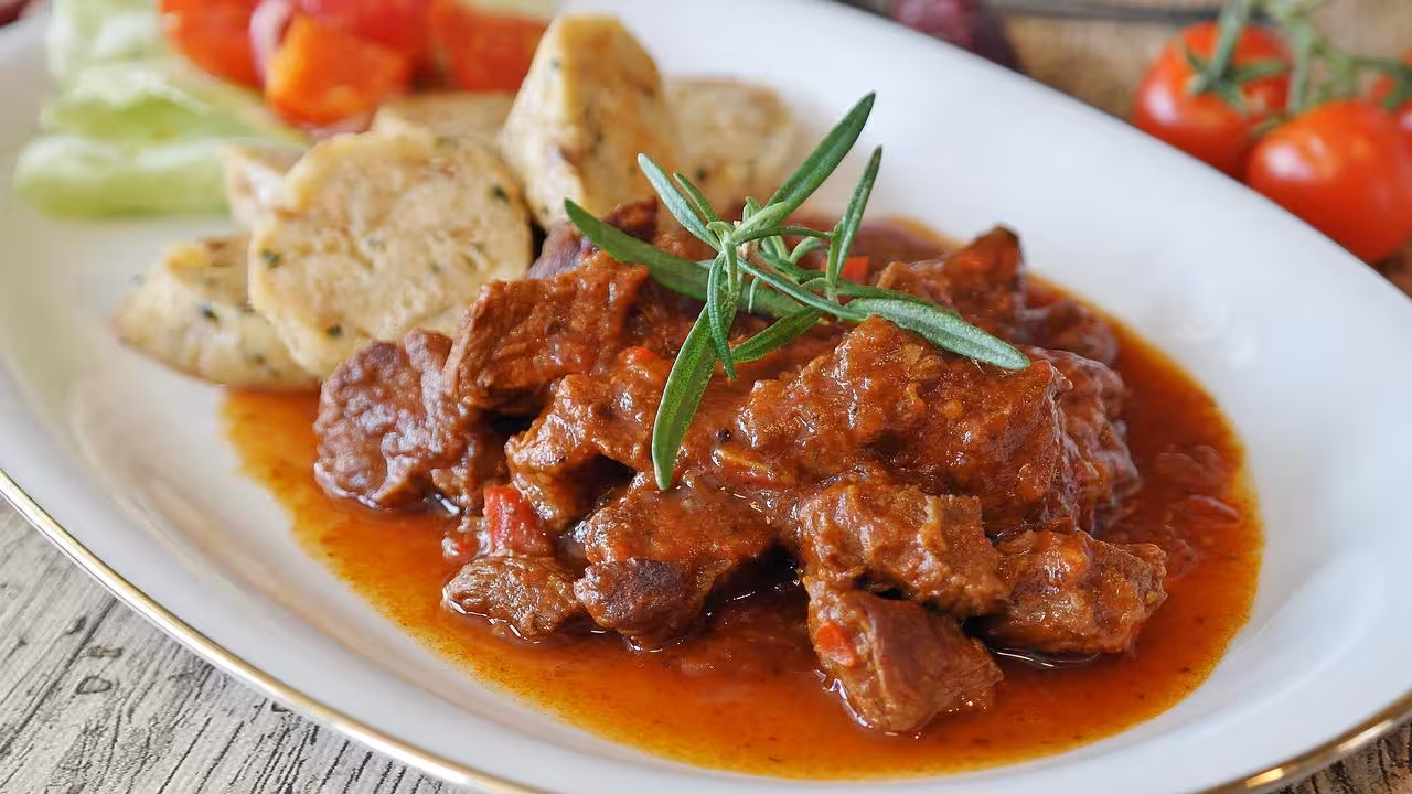 Rich beef stew served with vegetables and dumplings, a culinary highlight of the Conil Beef Festival Day Trip.