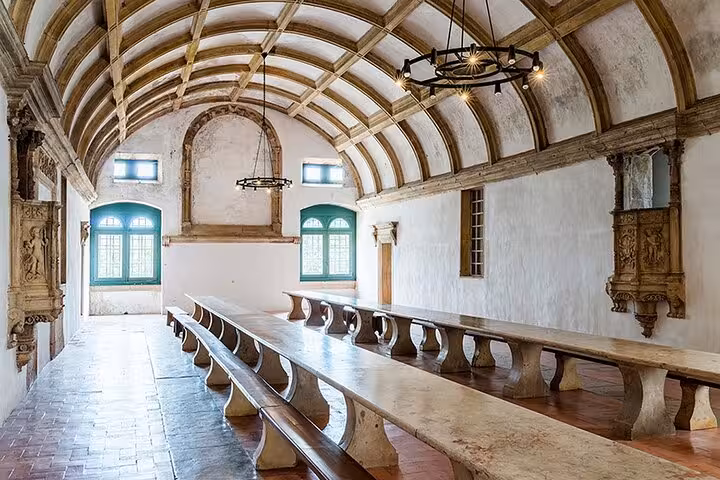 Historic dining hall in the Convent of Christ, Tomar, with arched ceilings and long wooden tables.