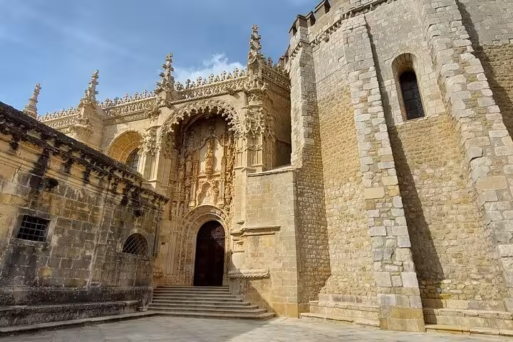 Marvel at the intricate Gothic entrance of the Convent of Christ in Tomar during a private walking tour.